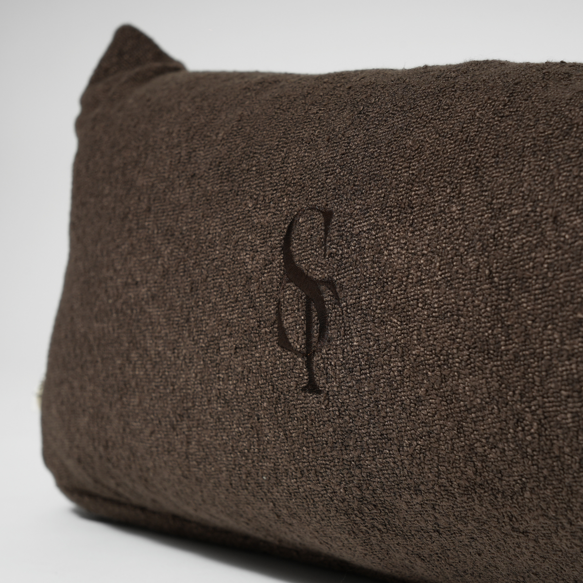 Close-up of the embossed Staey monogram on dark brown wool