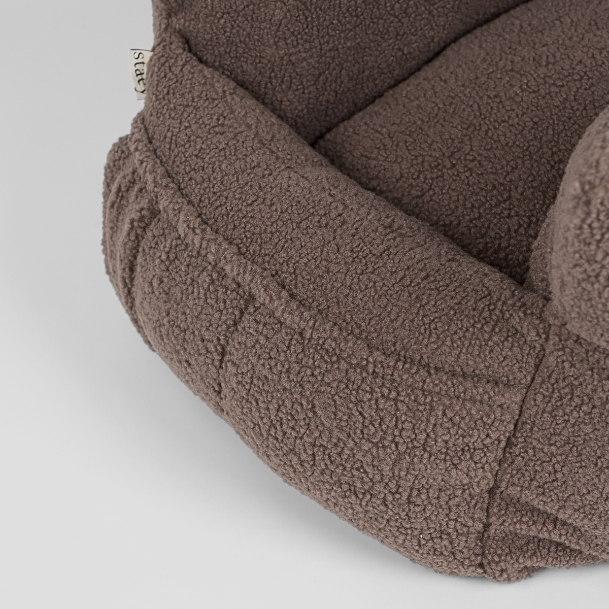 Close-up of the quilted lining and bolster inside the Clara teddy car seat