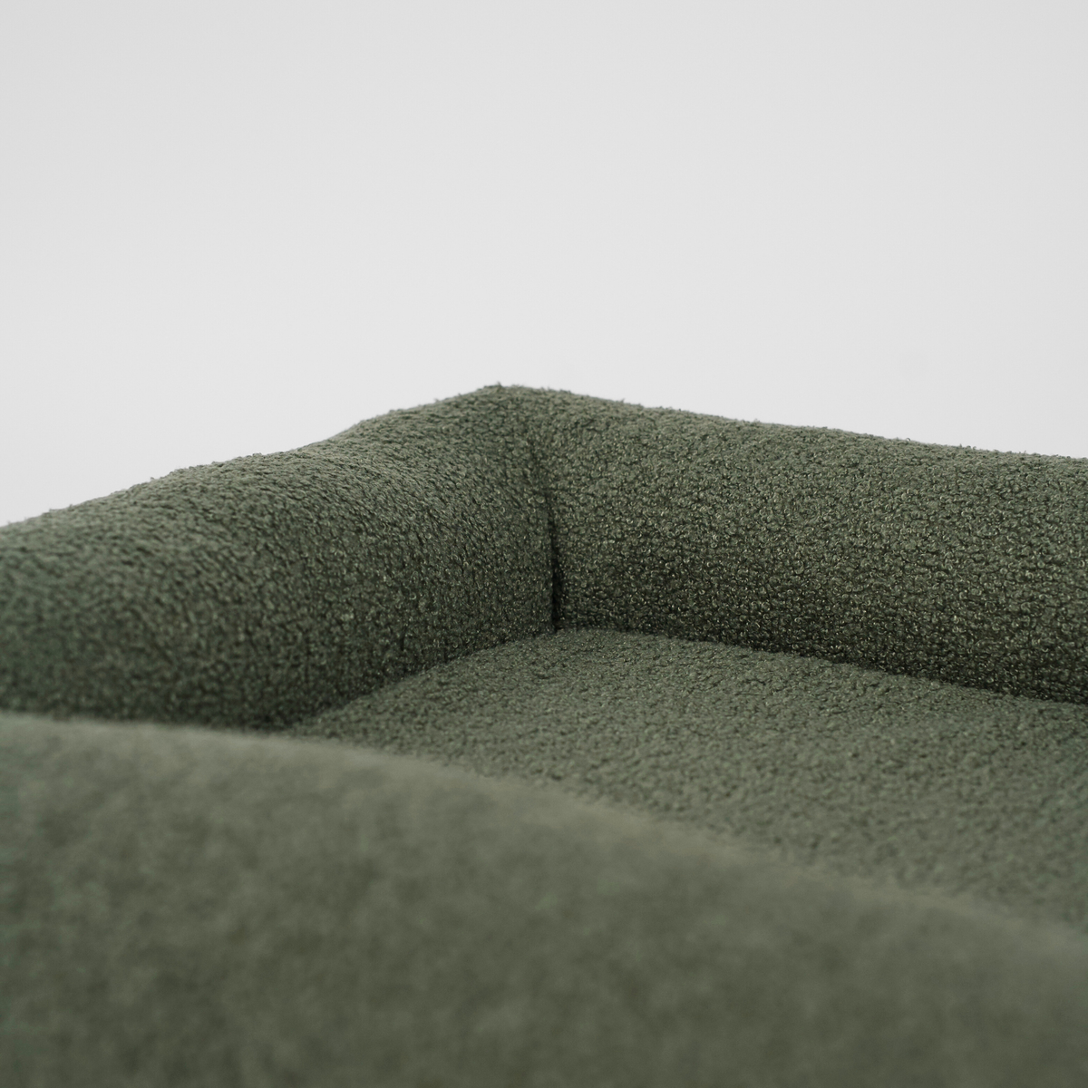 Close-up of the bolster and cushion in a moss green bouclé dog bed