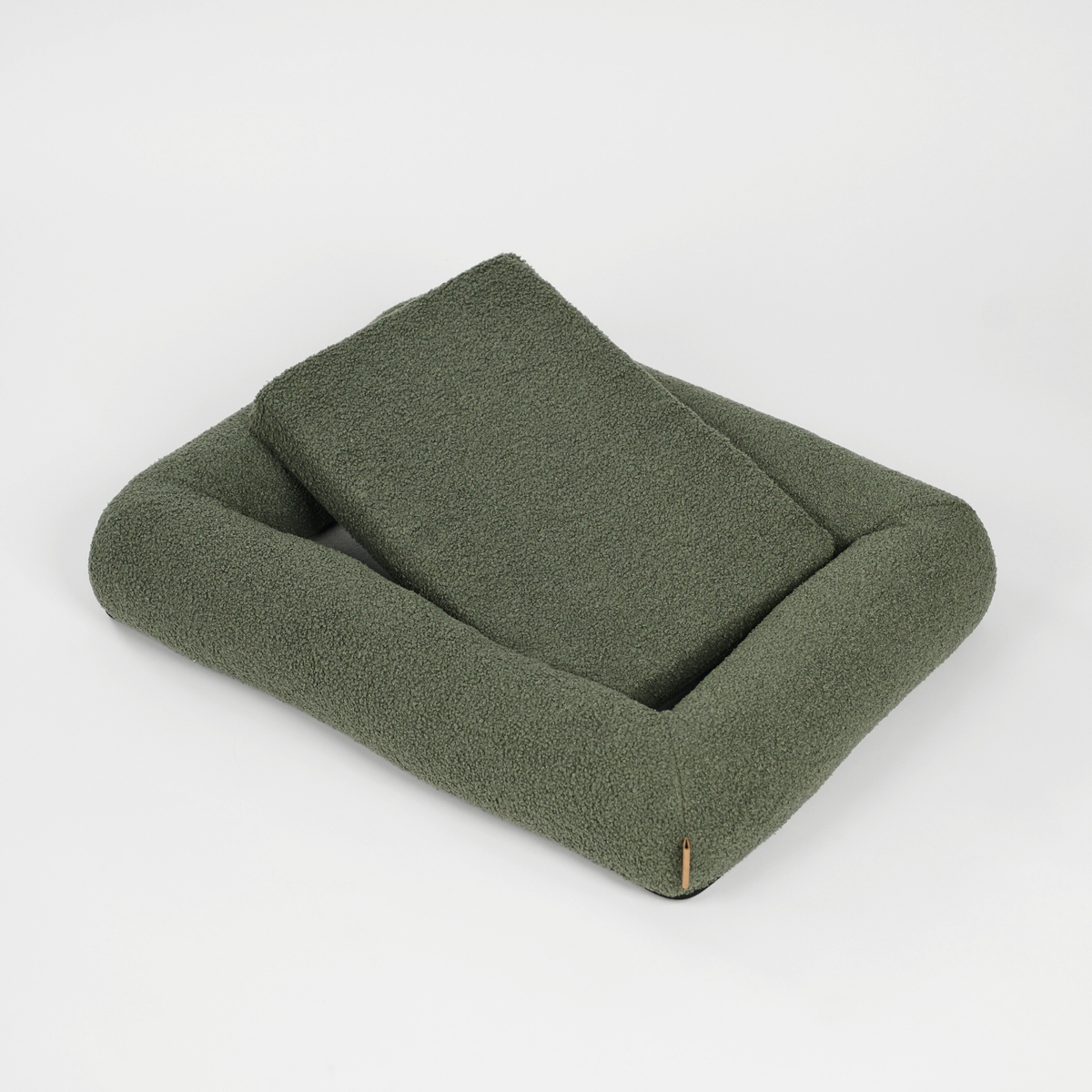 The moss green bouclé dog bed with its cushion propped up