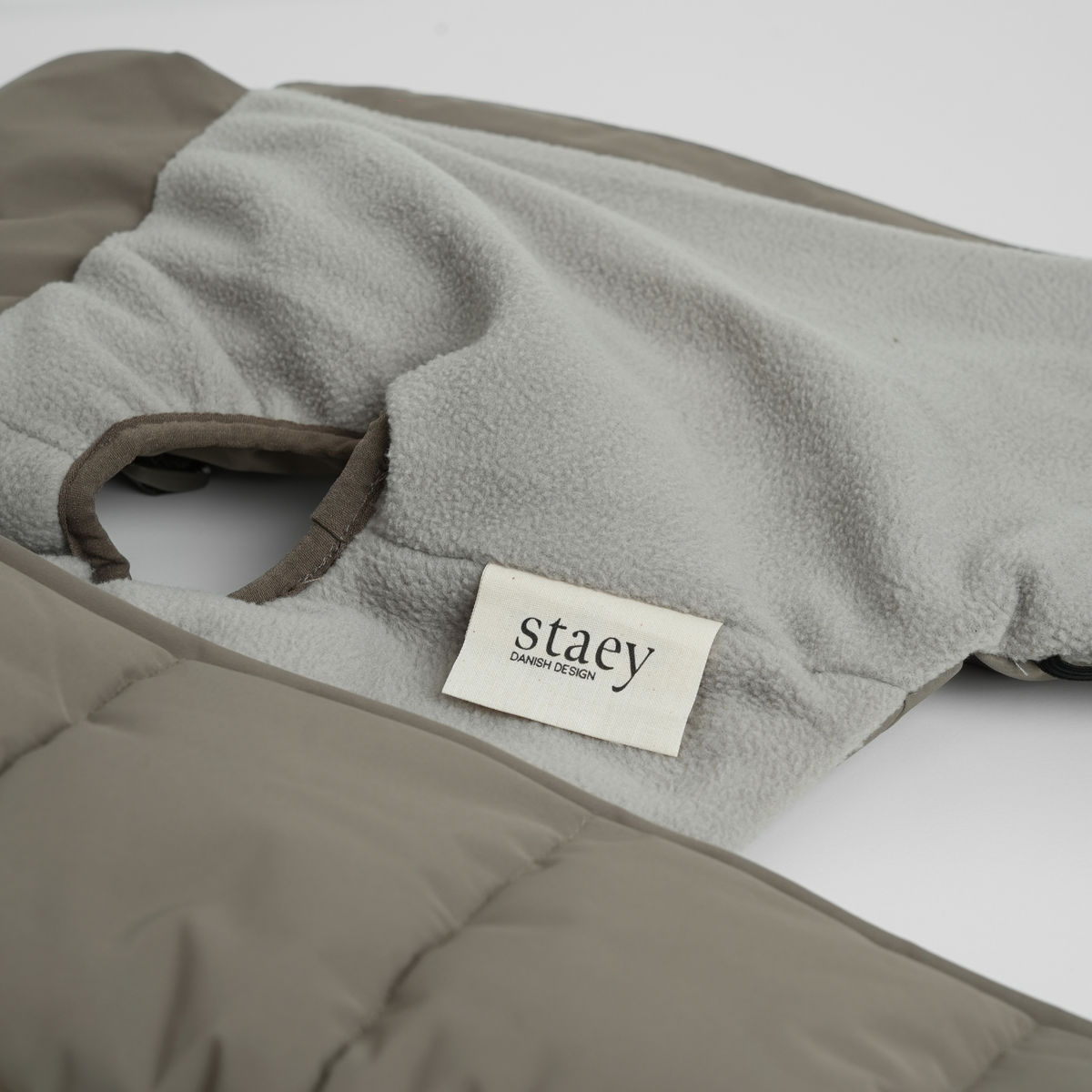 Close-up of the Staey label and fleece lining on the taupe quilted coat