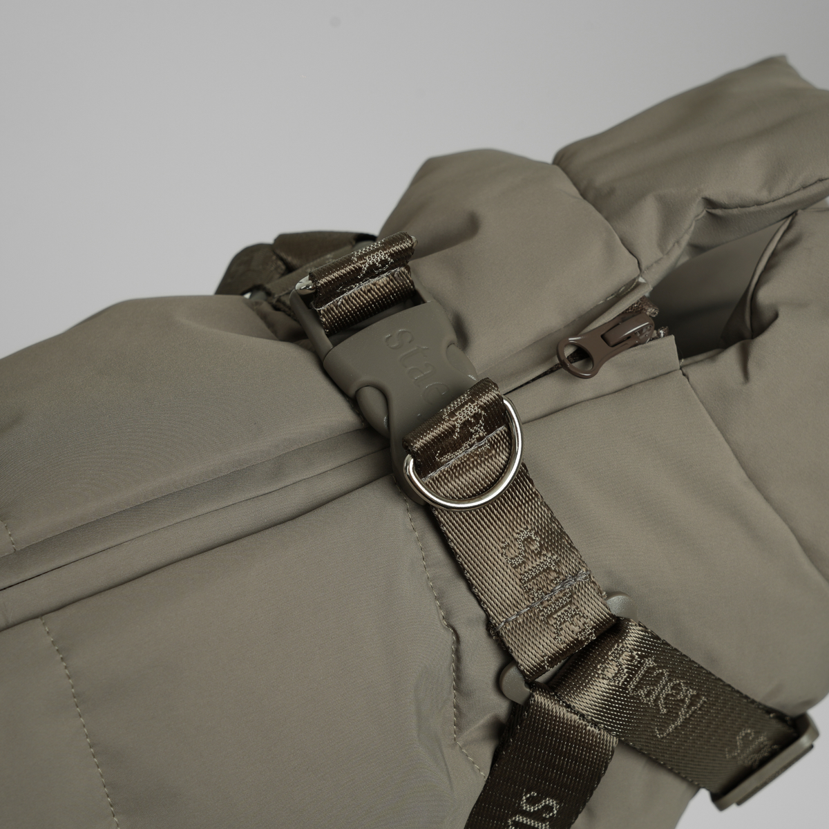 Close-up of the D-ring and Staey webbing on the taupe quilted coat