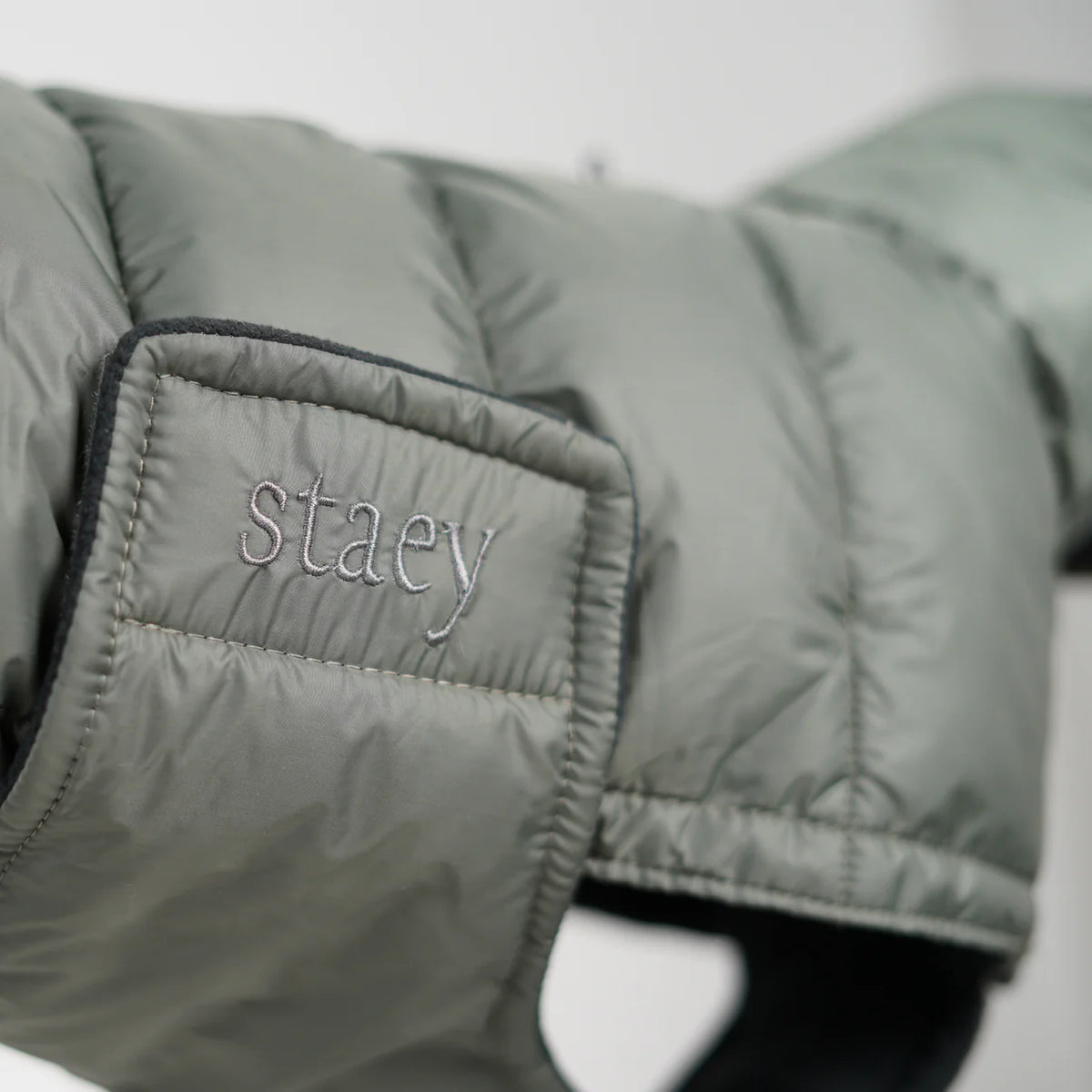 Close-up of the embossed Staey patch on the Nora quilted coat