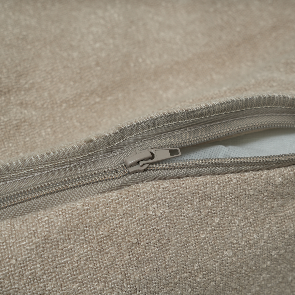 Close-up of the zip on the removable cover of the oat bouclé Luna bed