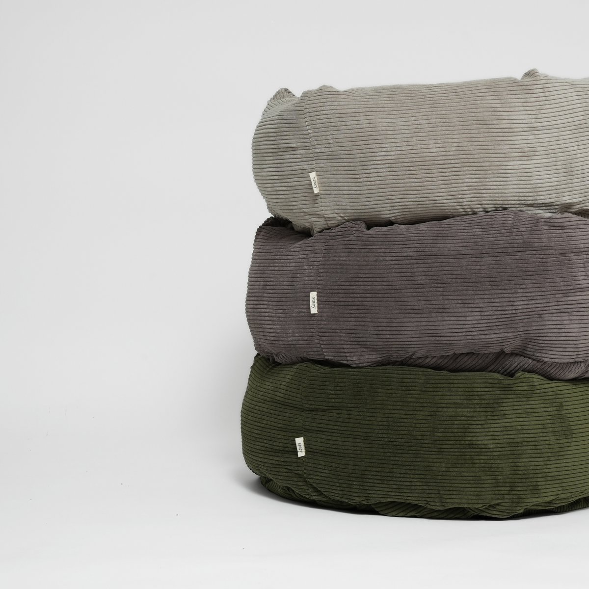 Three corduroy dog beds stacked in dune, taupe and moss green