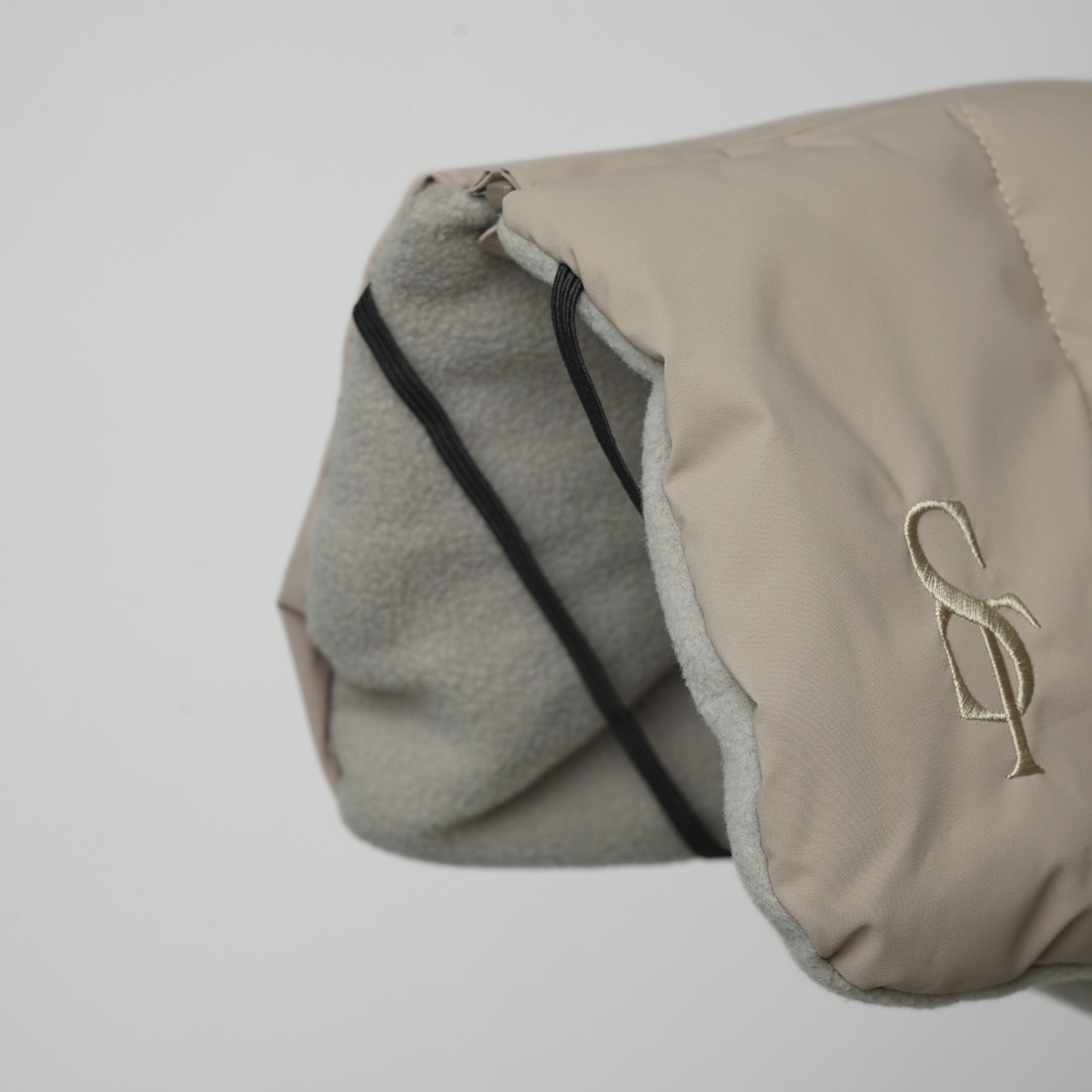 Close-up of the embossed Staey monogram and fleece lining on a taupe dog blanket