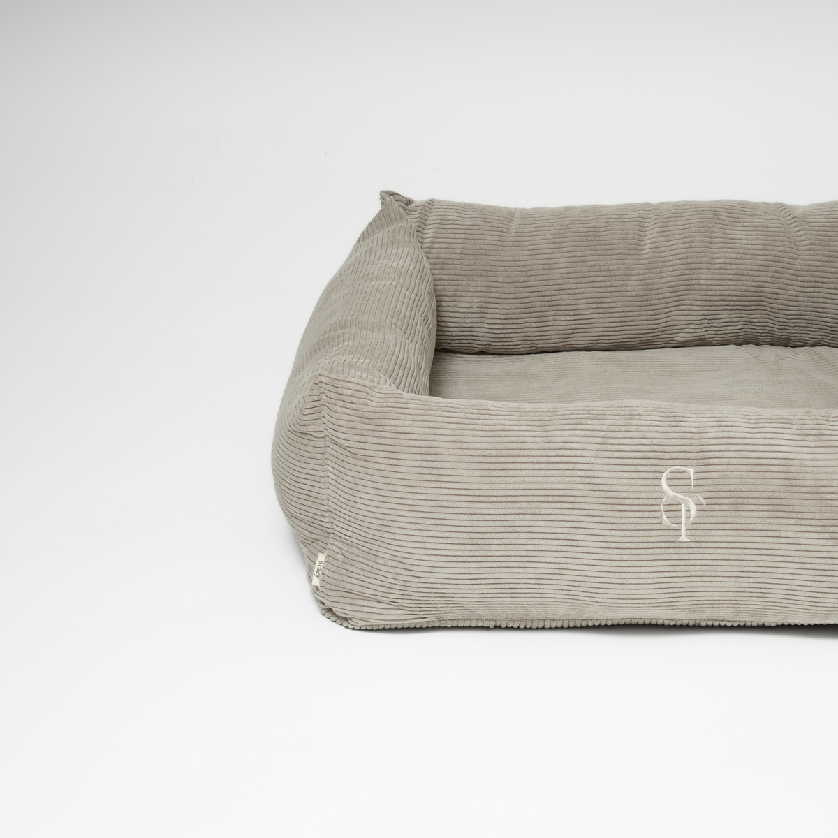 Den rektangulære hundeseng i taupefarvet fløjl med det prægede Staey-monogram