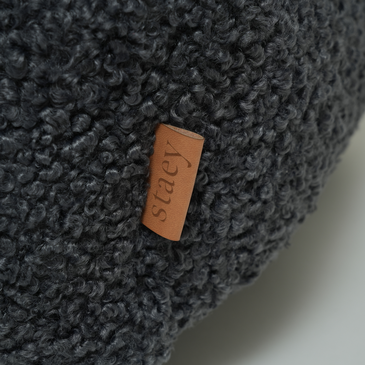 Close-up of the leather Staey tab on the storm curly bouclé dog bed