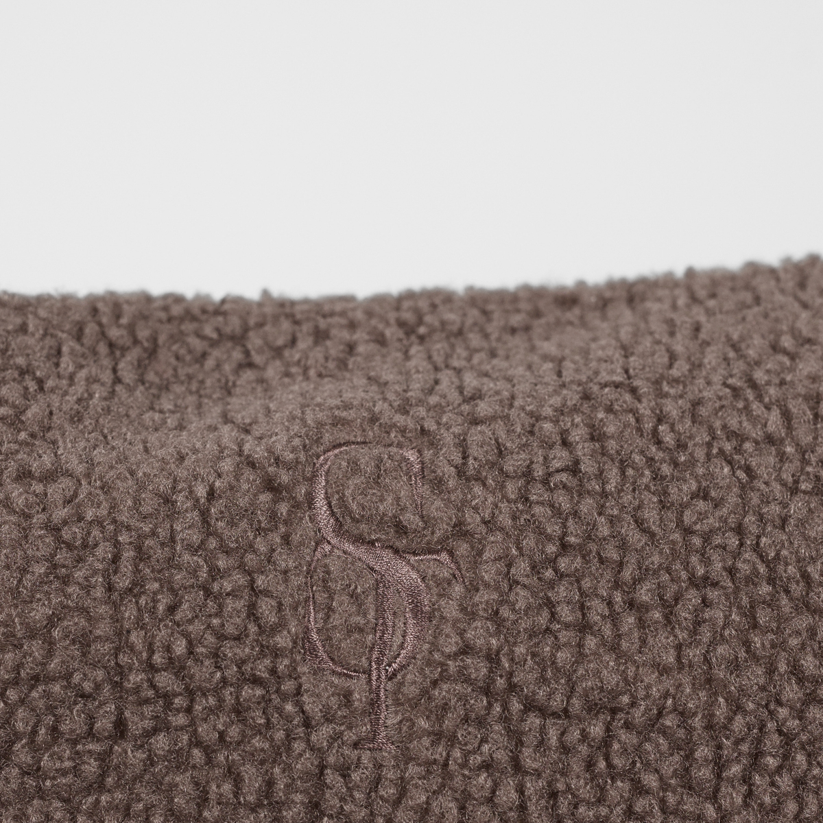 Close-up of the embossed Staey monogram on the Clara teddy fabric