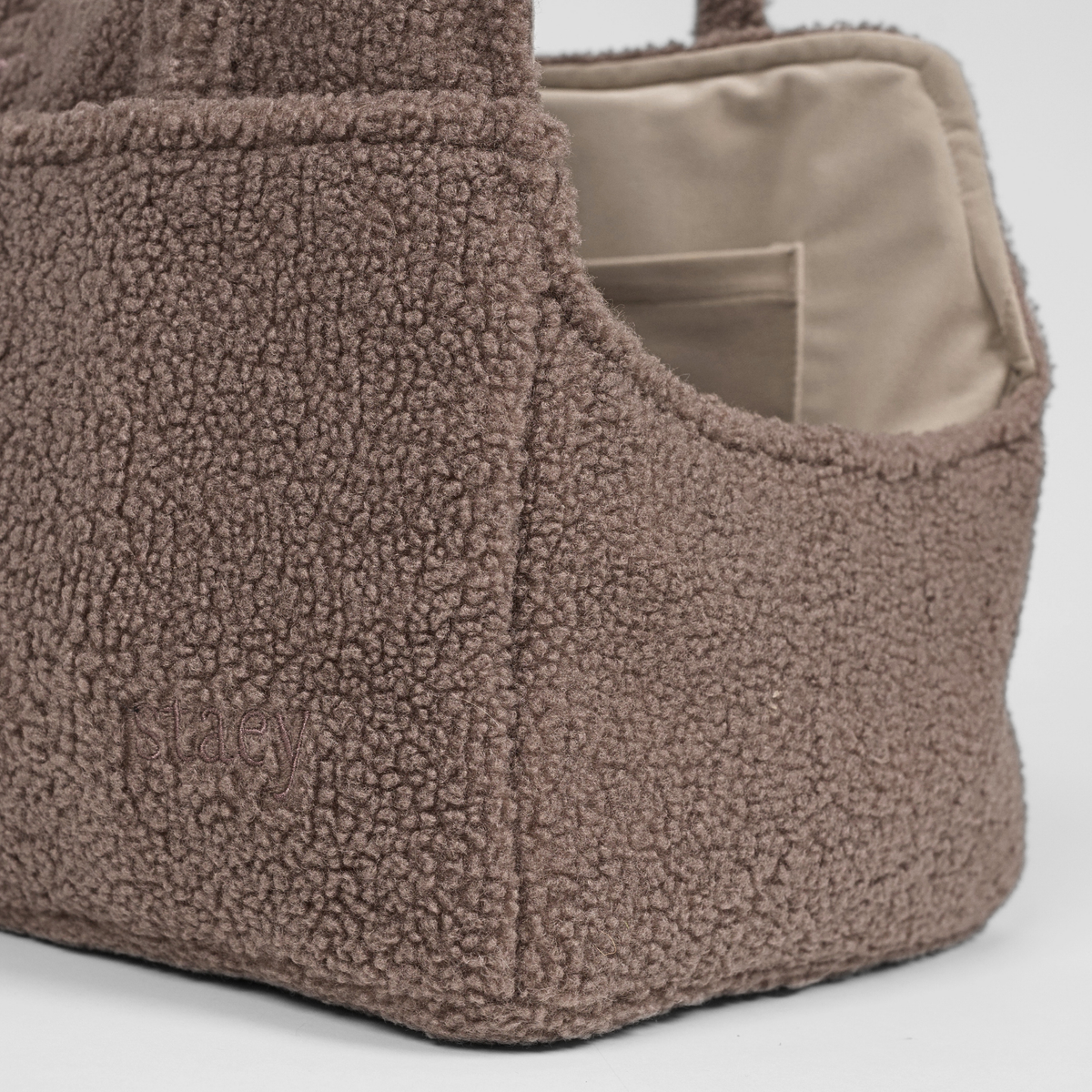 The Clara teddy carrier bag seen from the side with its embossed Staey mark