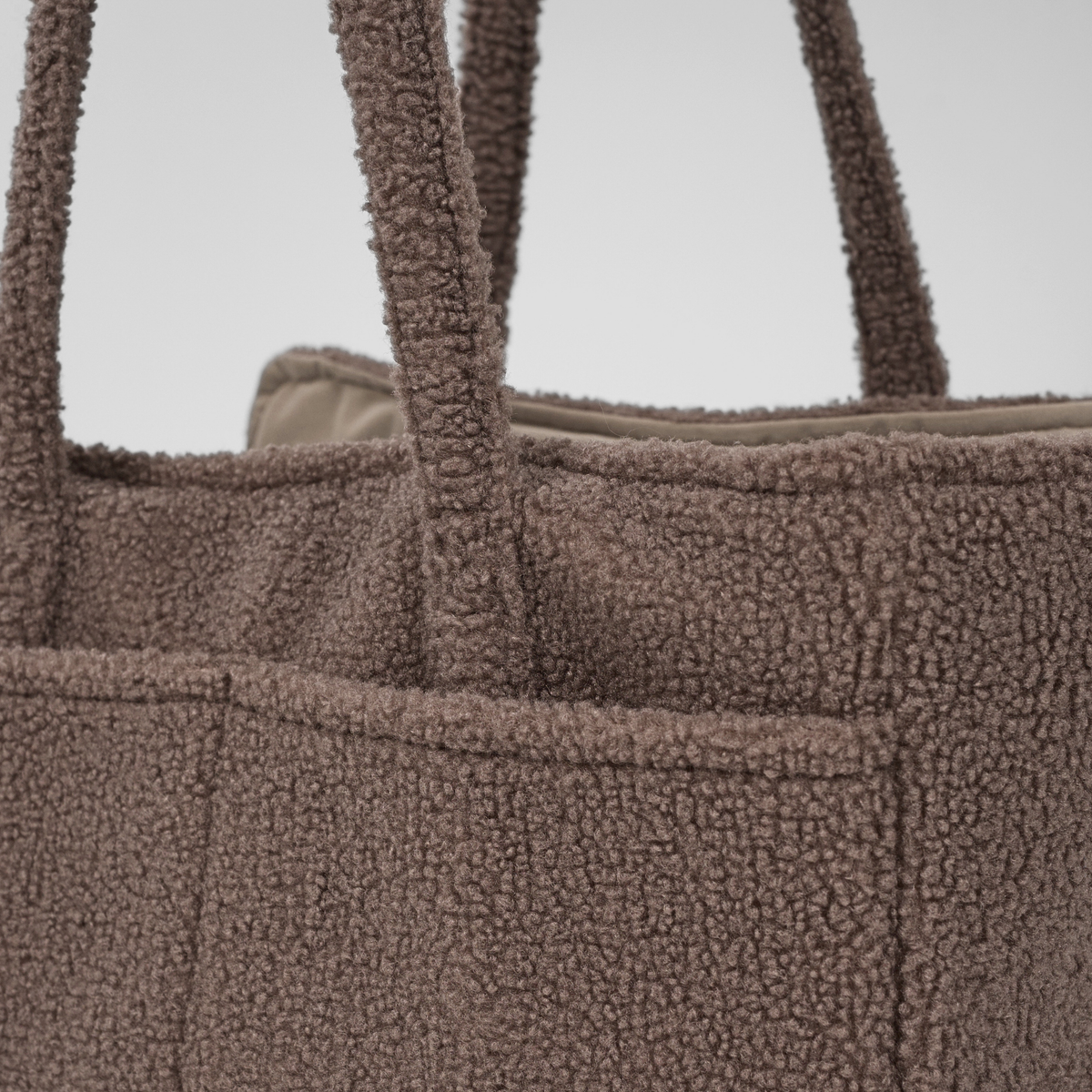 Close-up of the handles and side pocket on the Clara teddy carrier bag