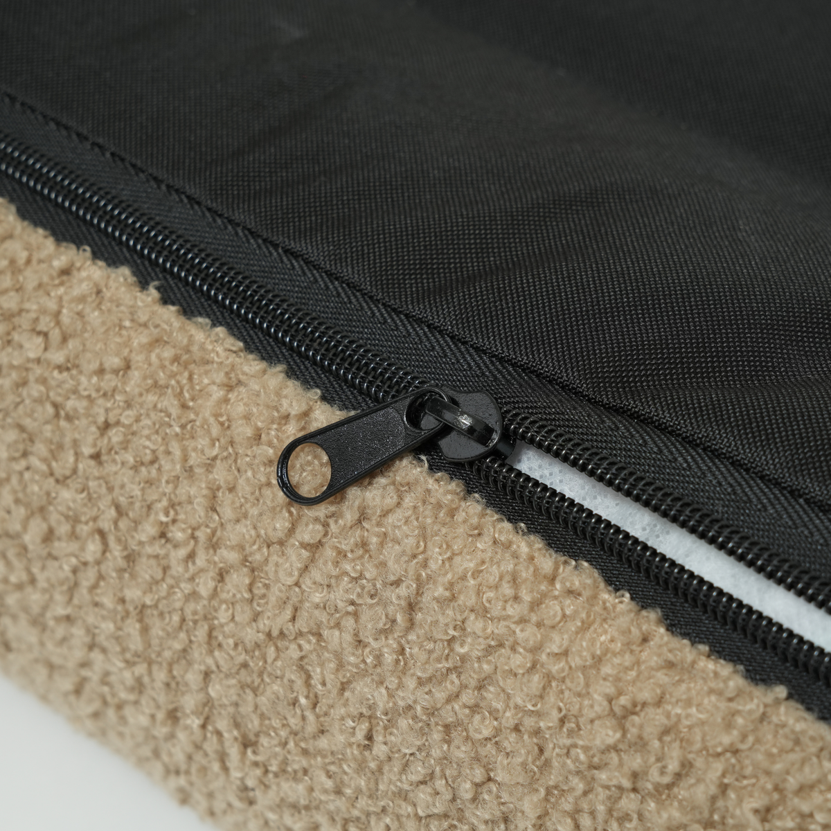 Close-up of the zip on the removable cover of the sand curly bouclé dog bed
