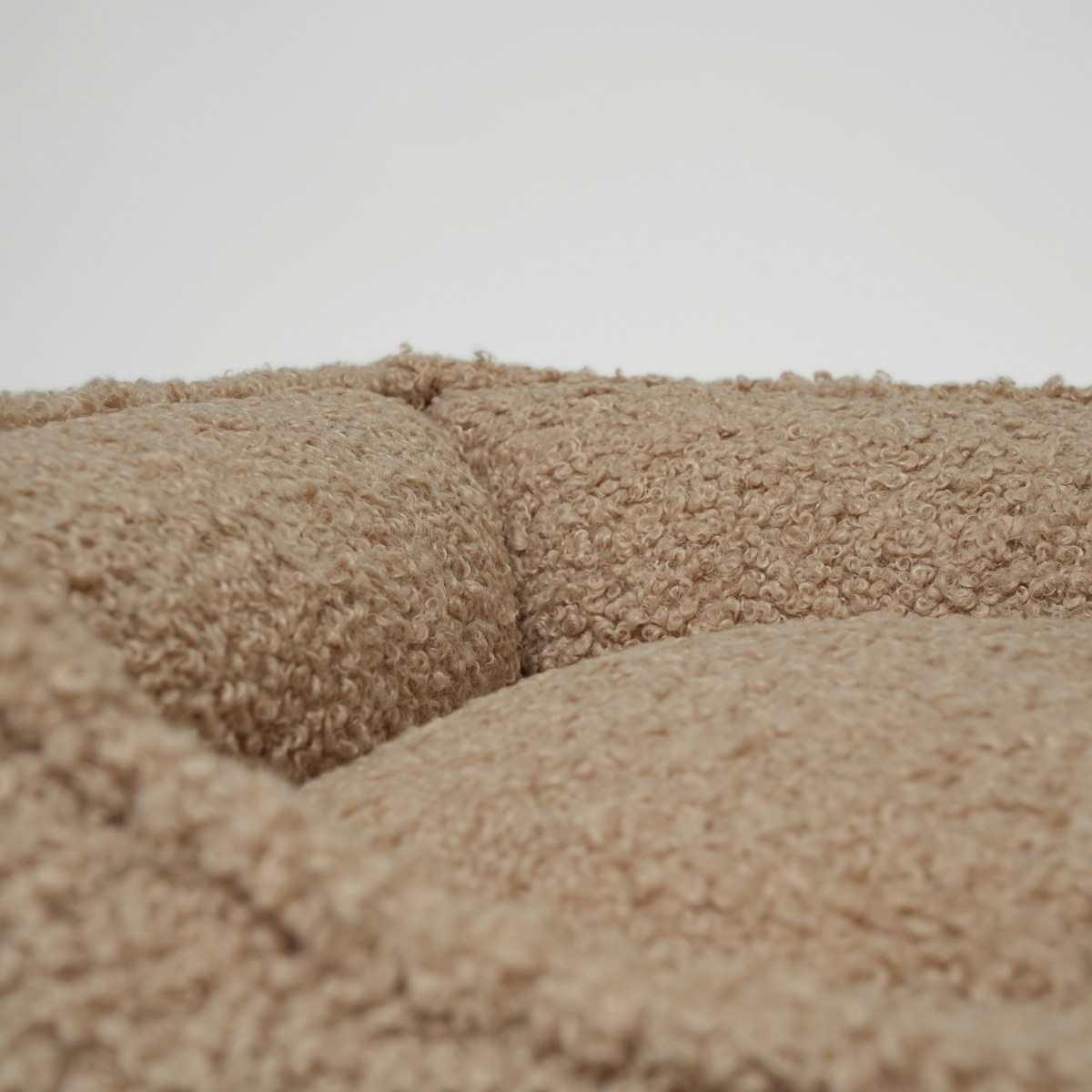 Close-up of the bolster and cushion in the sand curly bouclé dog bed