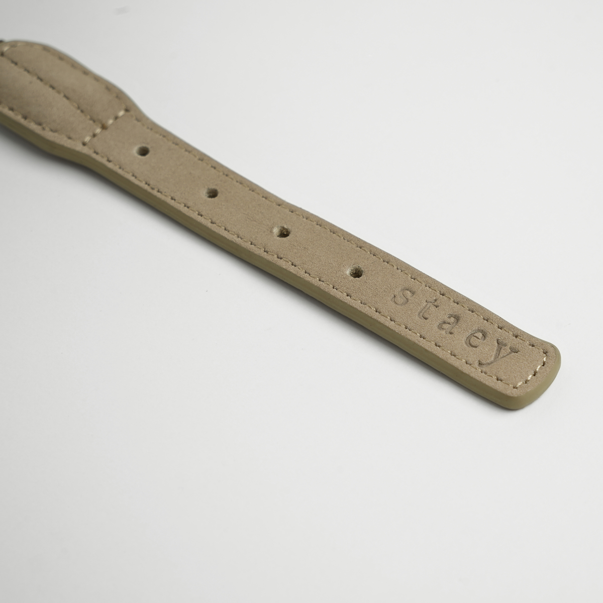 Close-up of the adjustment holes and Staey stamp on the taupe leather collar