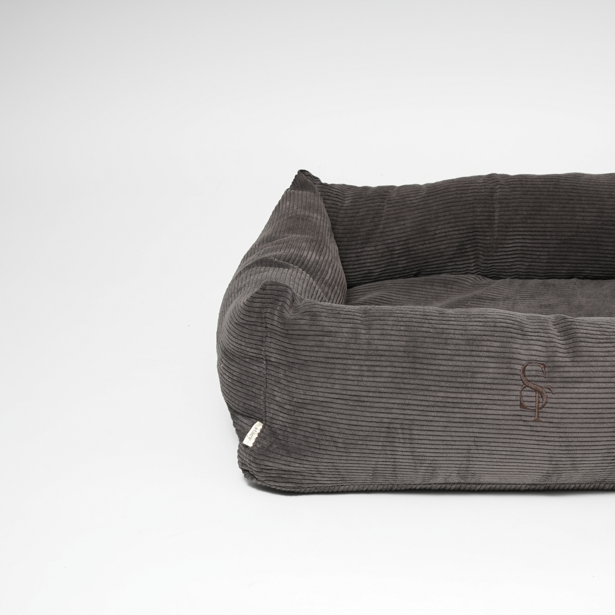 The charcoal corduroy rectangular dog bed seen at an angle